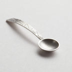 Silver decorative spoon on a light grey background. sterling silver christening baptism spoon for godson goddaughter with engraved design on a textured stone surface being held in a hand nottingham