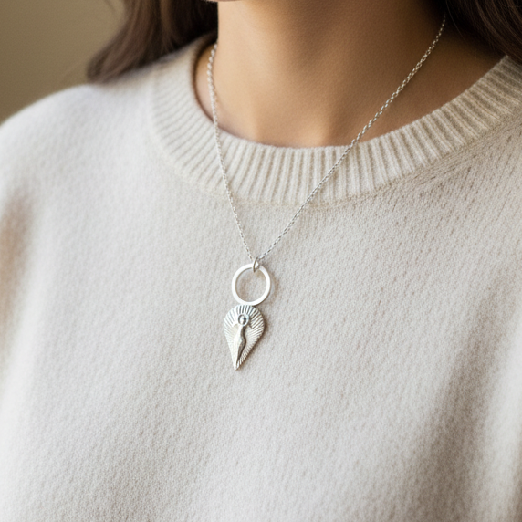 Woman wearing a silver necklace with a unique mother goddess pendant which symbol of protection, feminine power and spiritual connection on a beige sweater.