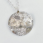 Silver pendant with floral and hummingbird design on a white background