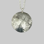 Silver pendant necklace with floral and bird design on a grey green background handmade by Bottlebee in Nottingham