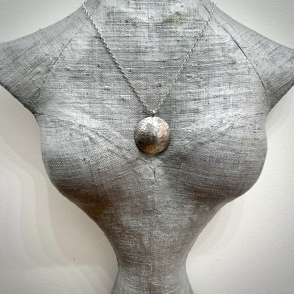 Mannequin wearing a silver necklace with a textured pendant on a light grey background, necklace sustainably handmade in Nottingham by Bottlebee