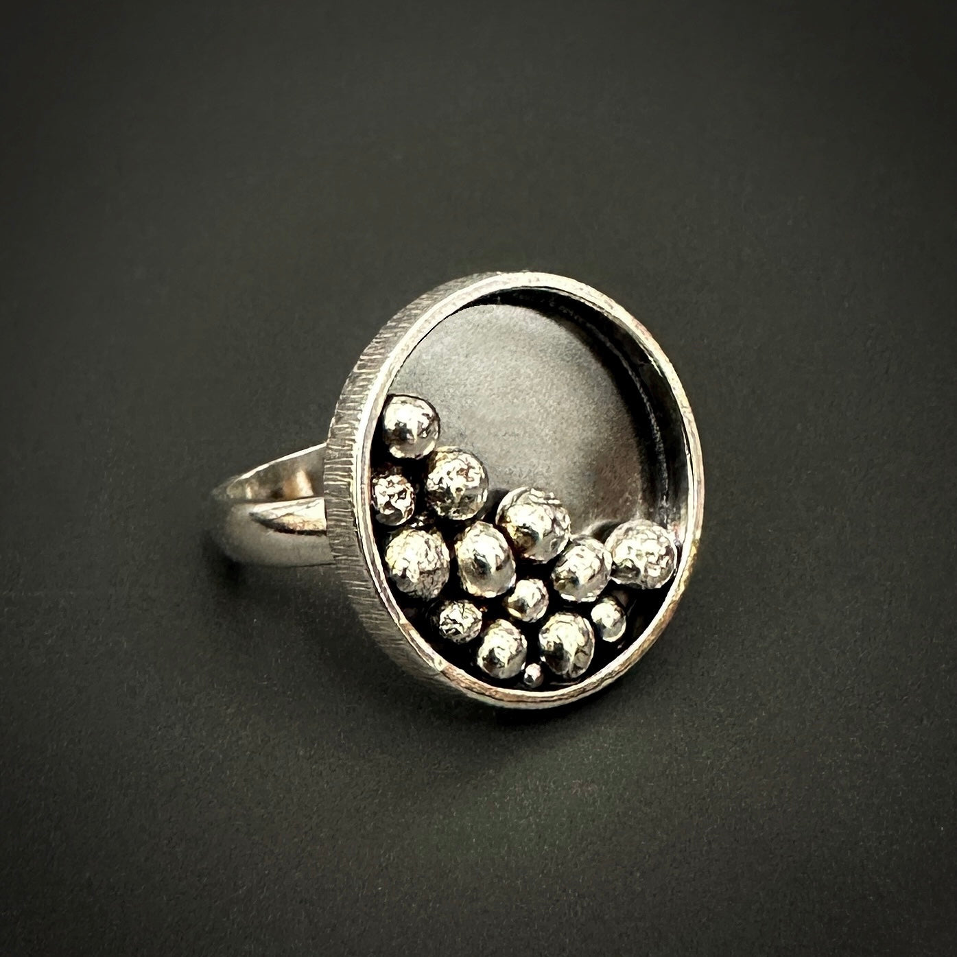 Sterling silver statement ring with spherical silver ball elements on a dark background