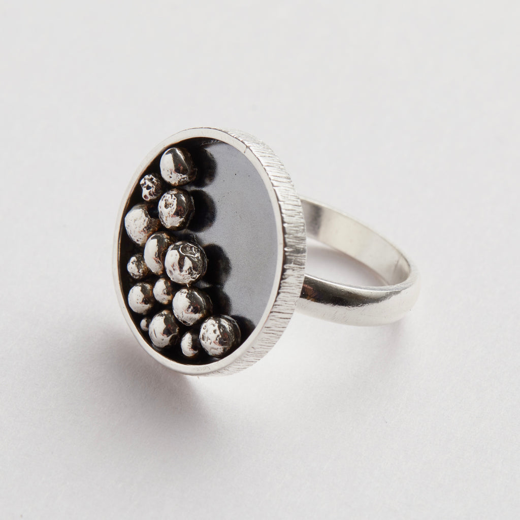 Silver ring with embedded silver balls on a light grey background handmade sustainably in Nottingham