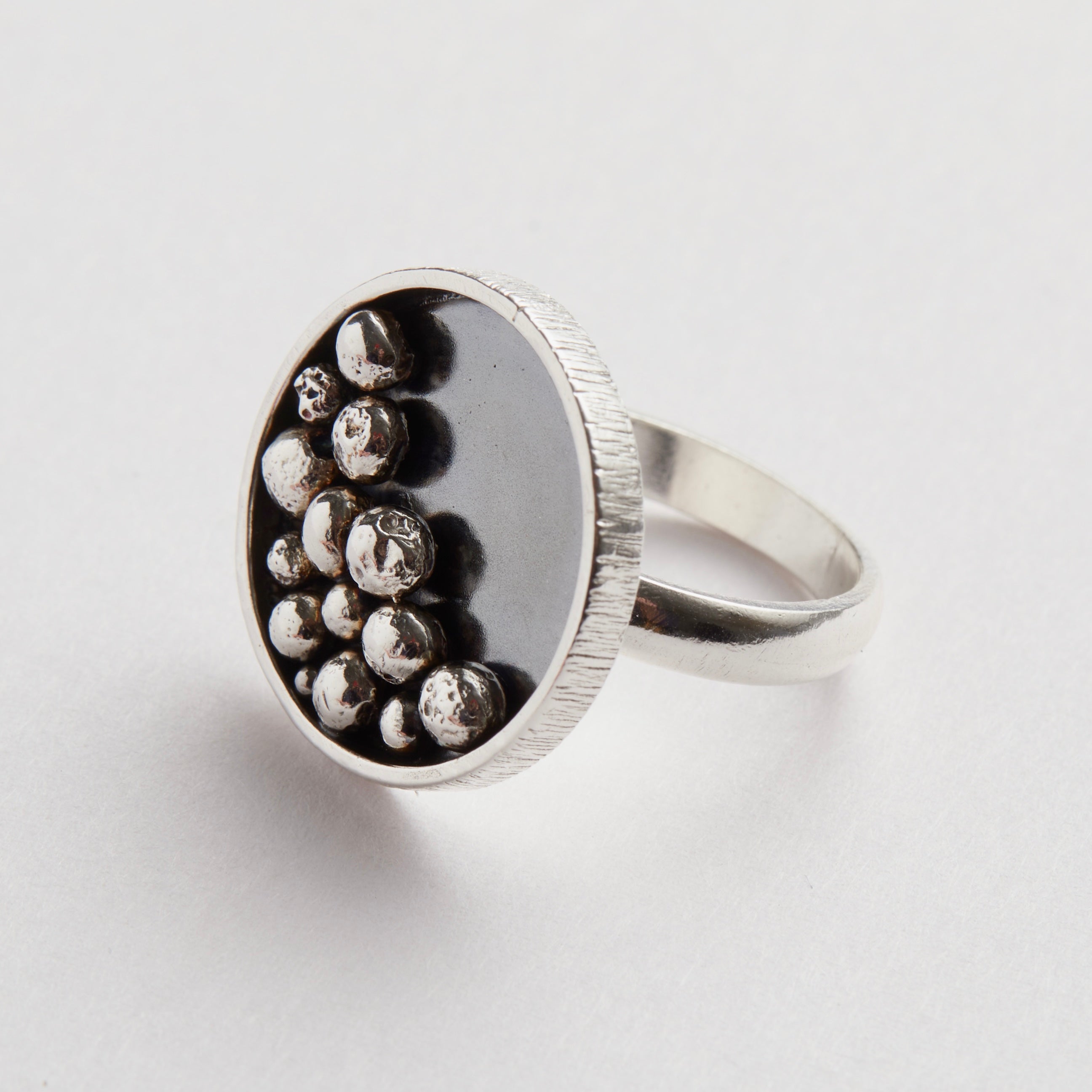 Silver ring with embedded silver balls on a light grey background handmade sustainably in Nottingham