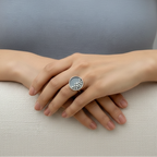 A woman wearing a blue grey top resting her hands on a cream sofa, wearing a silver ring which has been oxidised and has silver balls surrounded by a raised circle