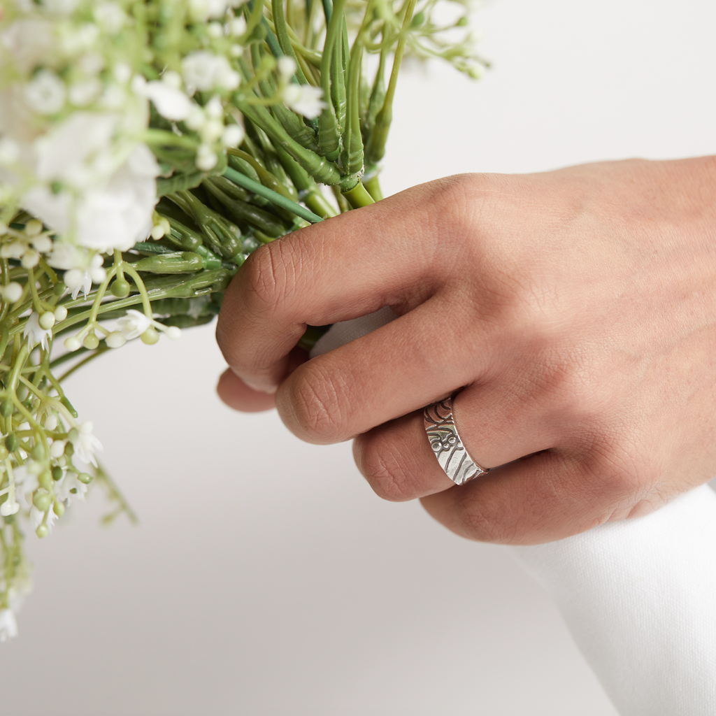 Bride holding a bouquet of flowers with a silver wedding ring on her hand , the ring is handmade by Bottlebee who makes sustainable bespoke jewellery in Nottingham
