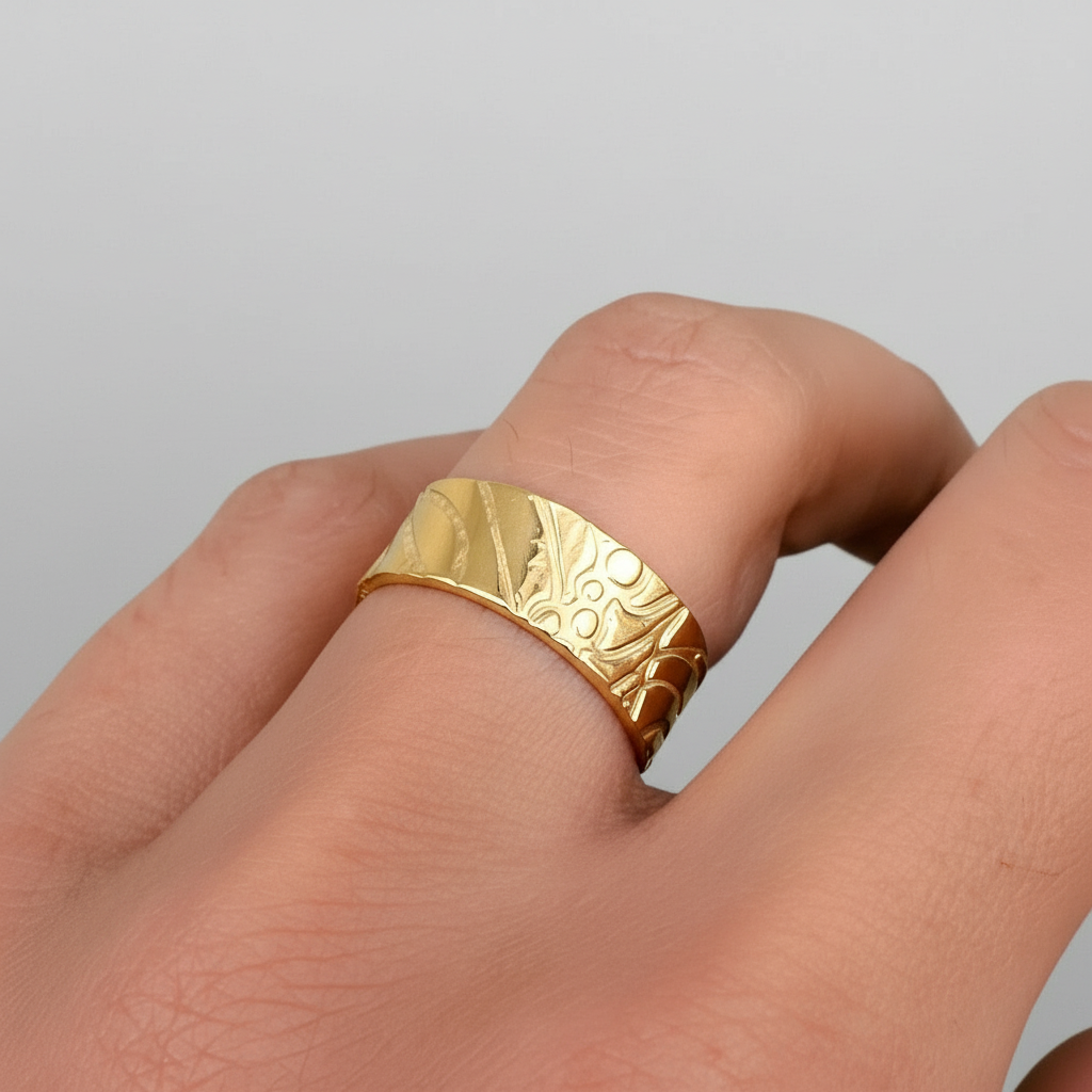 Solid gold wedding ring with a textured design on a finger against a white background, ring made by bottlebee who is a small business making sustainable jewellery in Nottingham