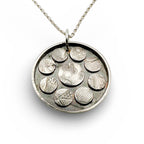 Silver necklace with a round pendant featuring embossed designs on a white background handmade sustainable jewellery by Bottlebee in nottingham