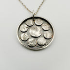 Silver necklace with a round pendant featuring embossed circular designs on a light grey background