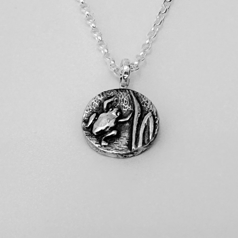Silver pendant necklace with a detailed frog design on a light grey background handmade by Bottlebee who makes bespoke sustainable jewellery in Nottingham