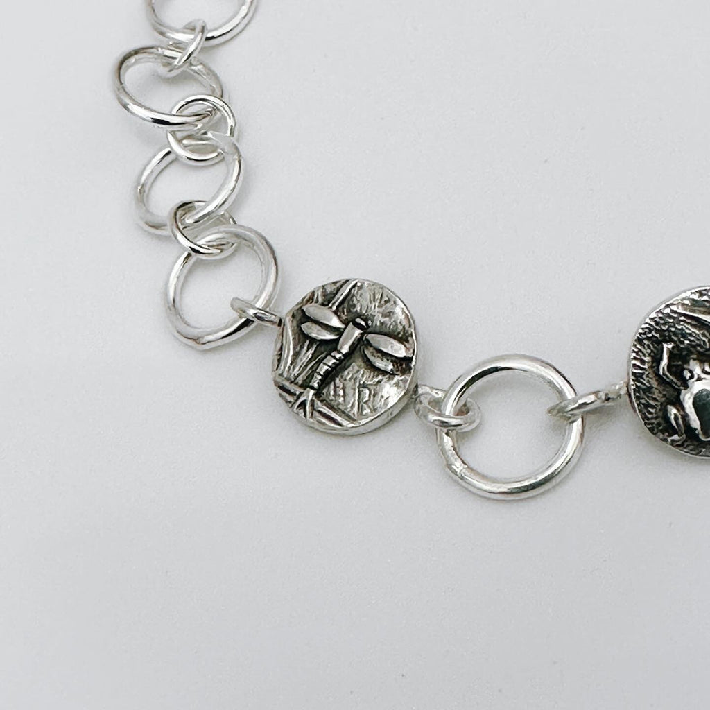 Close-up of a silver bracelet with dragonfly charm on a light grey background made in Nottingham