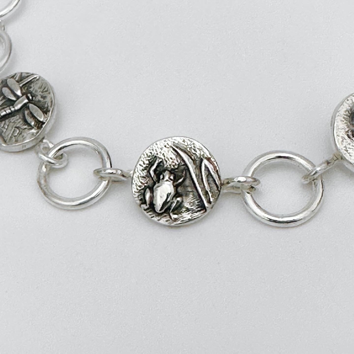 Close-up of a silver bracelet with from charm on a light grey background made in Nottingham by Bottlebee who mades jewellery that is sustainable