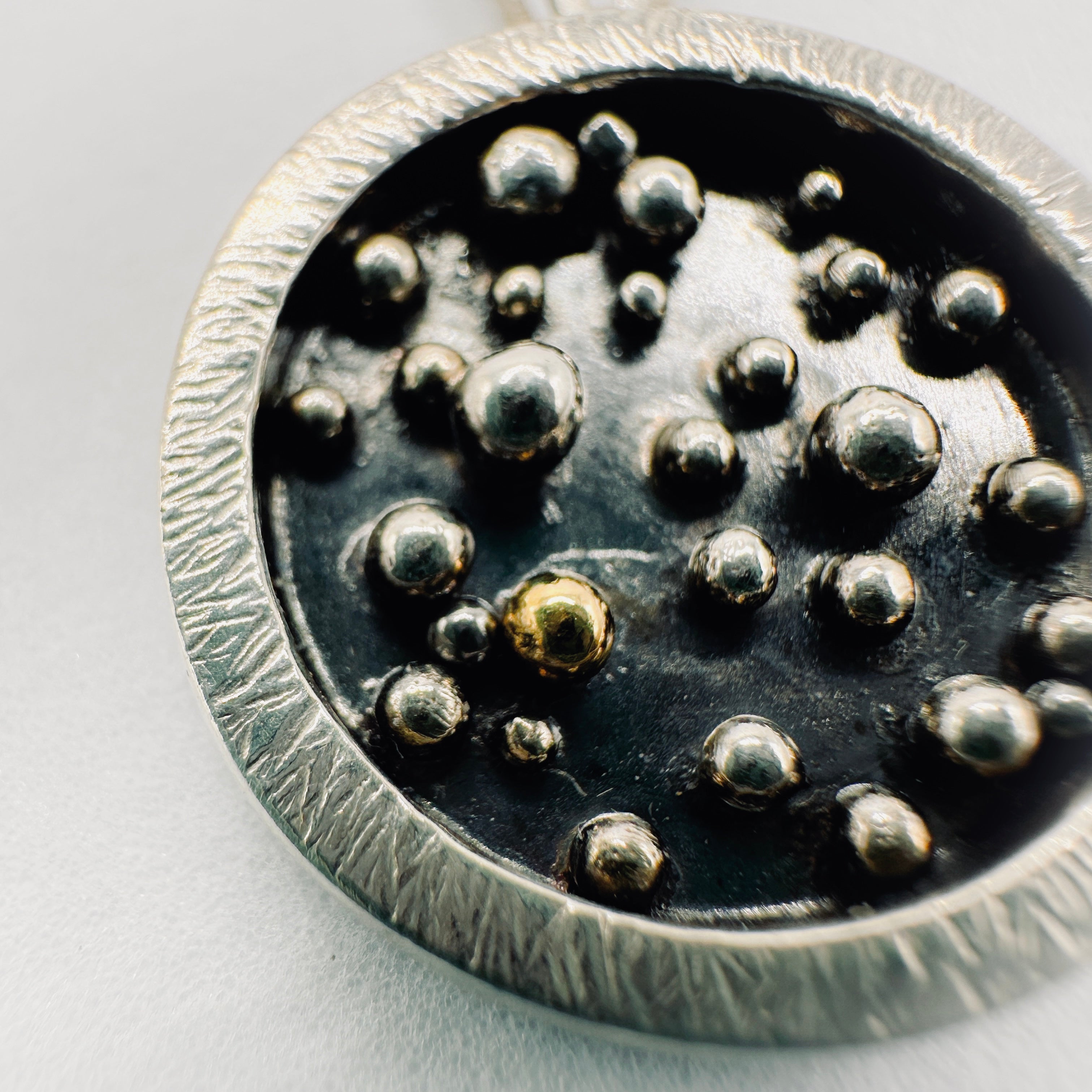 Close up of 18ct ball on oxidised silver pendant and paperclip chain necklace handmade in Nottingham by Bottlebee making sustainable bespoke jewellery