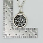 18ct gold and silver necklace with a circular pendant and 18ct gold and silver granuals next to a ruler for scale on a white background
