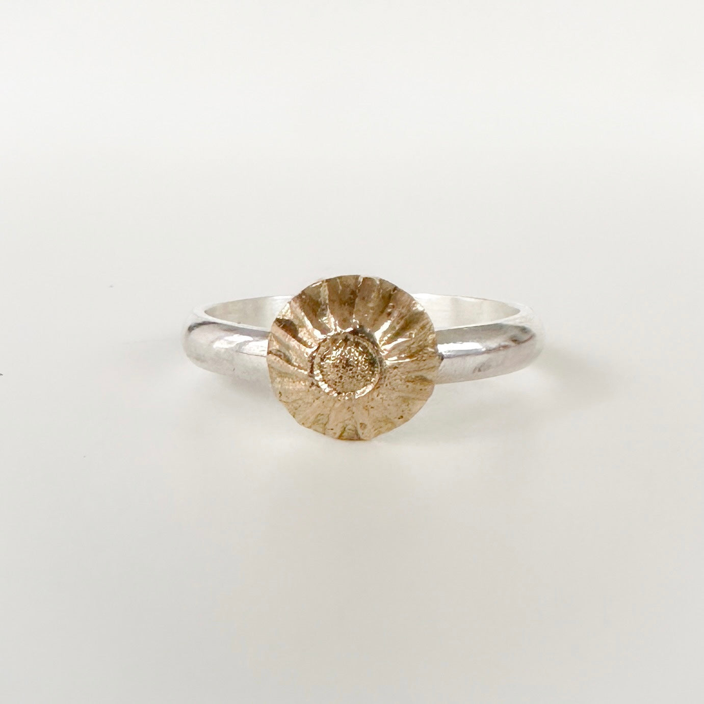 Face on view of silver ring with a gold center on a light grey background can be alternative engagement ring