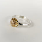 Side view of an alternative engagemnet silver ring with a ribbed textured gold accent on a light grey background