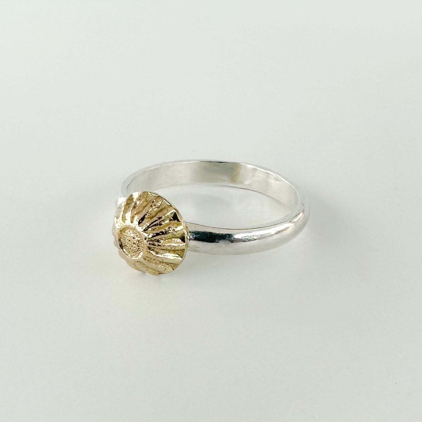 Unique and unusual Silver and gold engagement ring with a textured gold accent on a light grey background