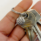 Hand holding a set of keys with a solid 925 sterling silver personalised keyring tag with an initial and decorative keychain