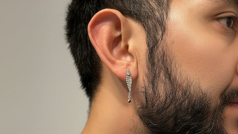 Close-up of a person wearing a handmade sterling 925 silver earring with a blurred light background