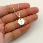 Silver necklace with a hexagonal pendant featuring the letter 'B' held in a hand and handmade in Nottingham in a sustainable way by Bottlebee