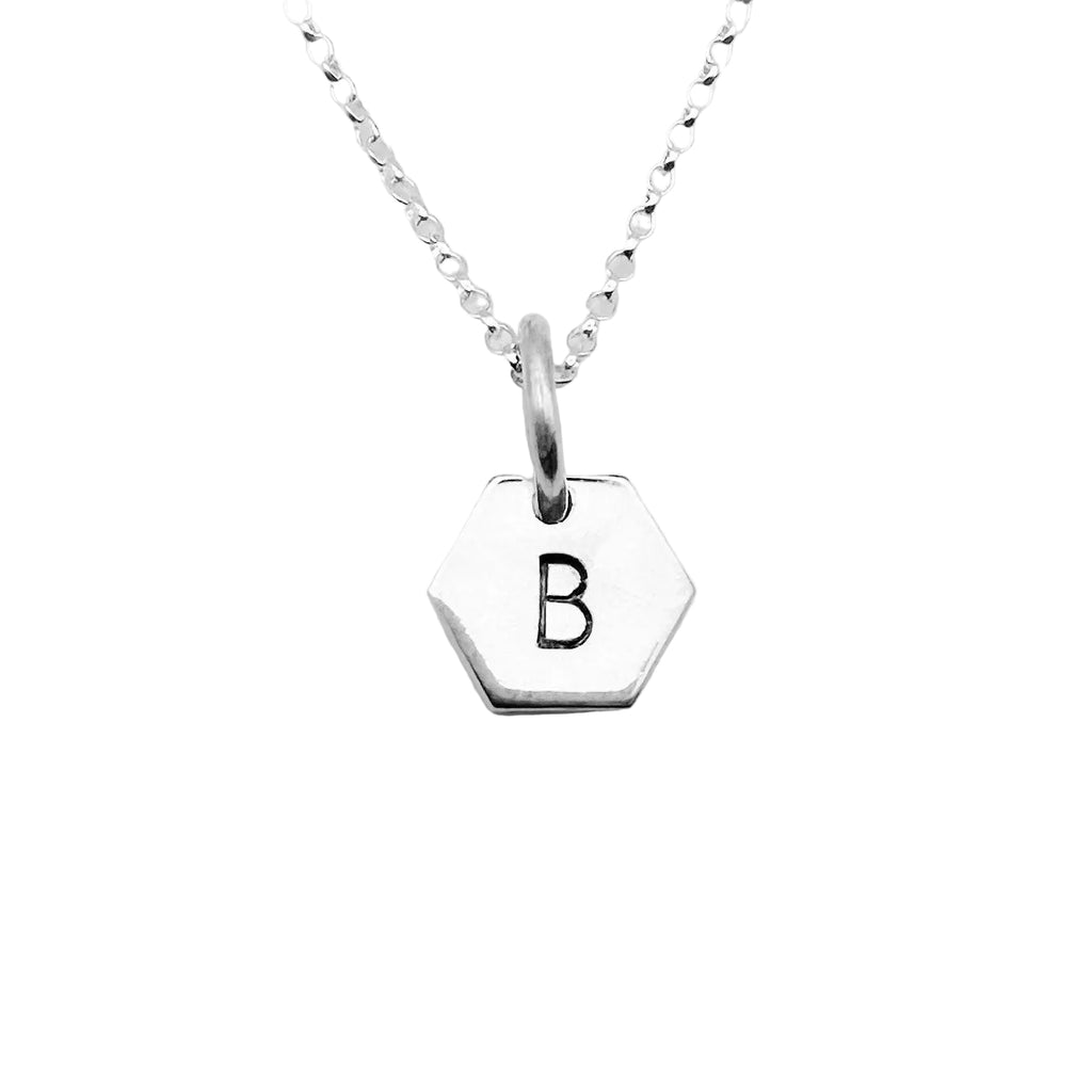 Silver necklace with a hexagonal pendant featuring a hand stamped letter 'B' on a light gray background made by Bottlebee in Nottingham