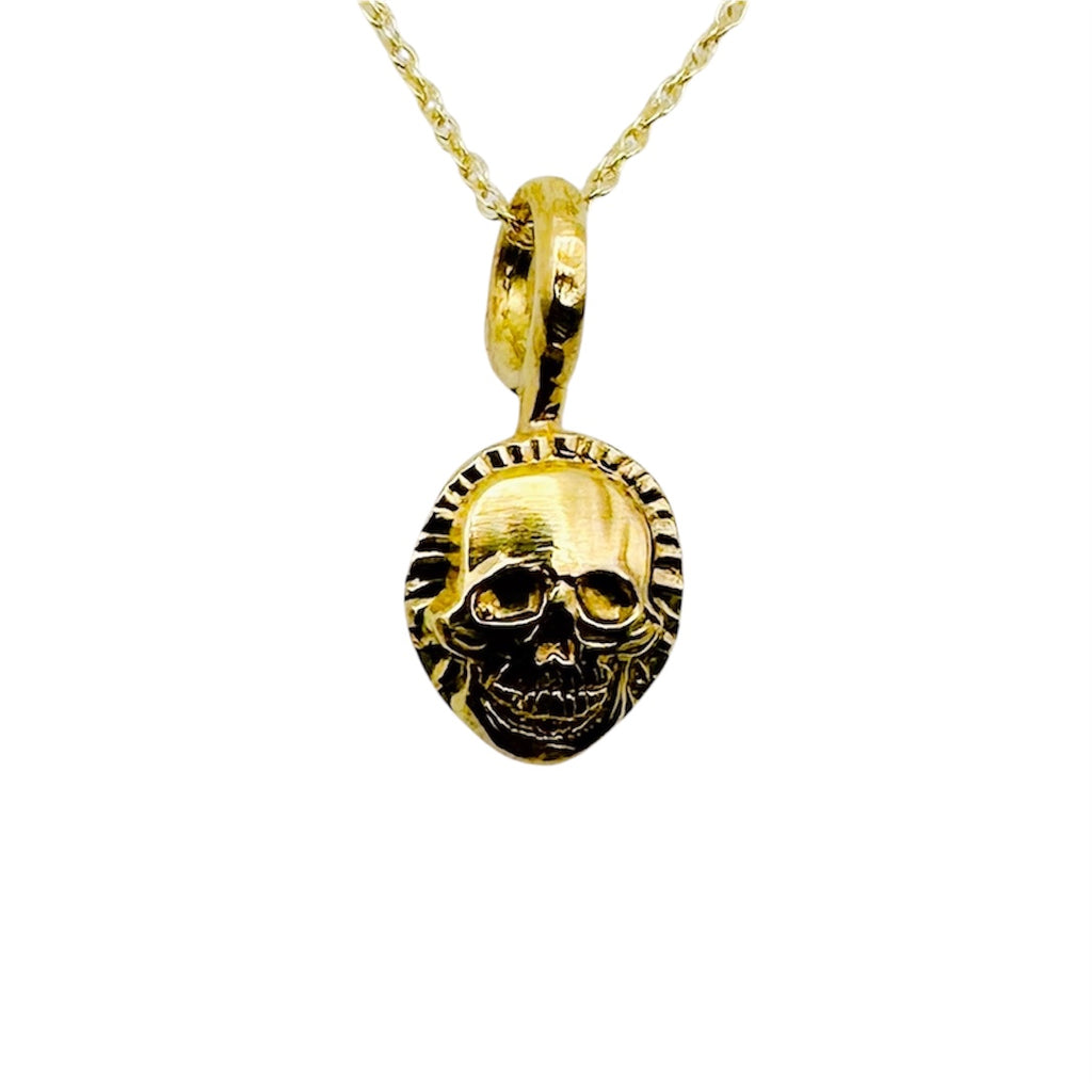 Handmade sustainable solid gold skull pendant on a chain against a white background