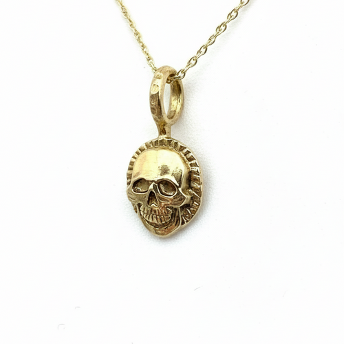 Gold skull pendant necklace on a light background handmade in Nottingham by Bottlebee