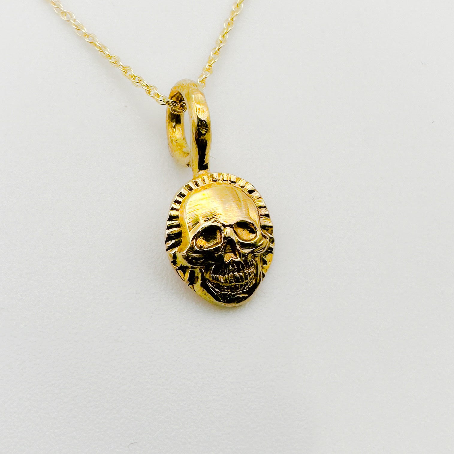Gold skull pendant necklace on a light gray background