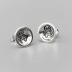 Silver earrings with a skull and crossbone design on a light background handmade by a small business called Bottlebee who makes sustainable jewellery in Nottingham