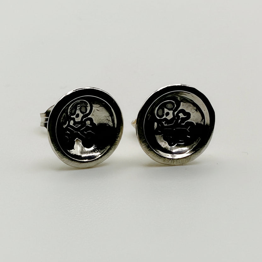 Pair of silver earrings with a skull emblem on a white background handmade by a small business called Bottlebee who makes sustainable jewellery in Nottingham