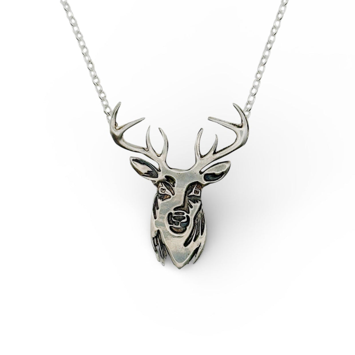 Silver deer face or stag face necklace on a white background handmade by Bottlebee in Nottingham who makes sustainable jewellery in silver and gold