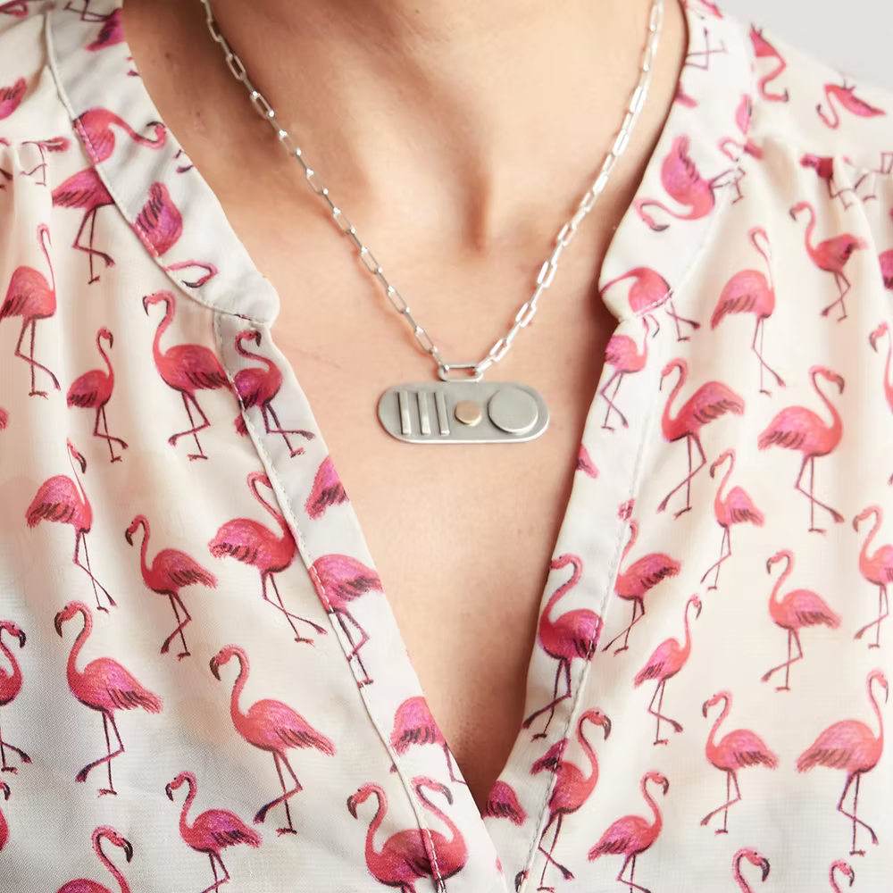 Woman in a pink flamingo shirt wearing a handmade in nottingham by a bespoke jeweller silver and gold necklace with a paperclip chain