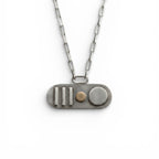 A handmade bespoke silver and 18ct gold oval necklace with 3 vertical line elements an 18t gold round element and a sterling silver larger round element hanging on a paperclip chain