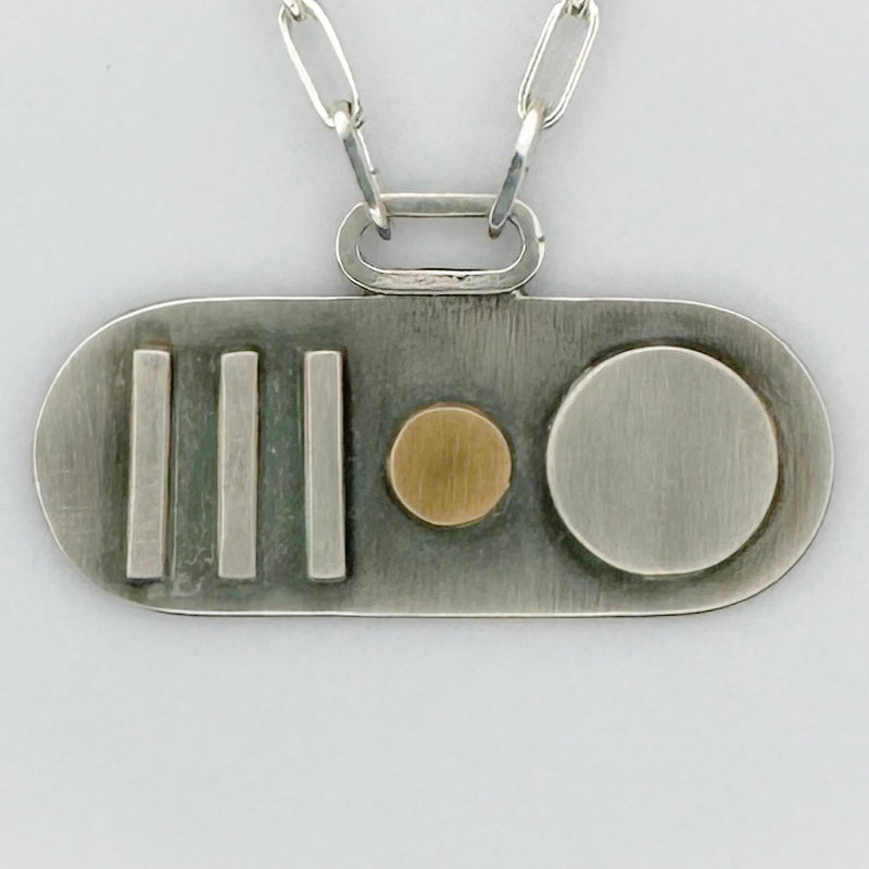 Sterling silver and gold pendant with geometric shapes and a paperclip necklace chain on a light grey background sustainably made by Bottlebee in Nottingham