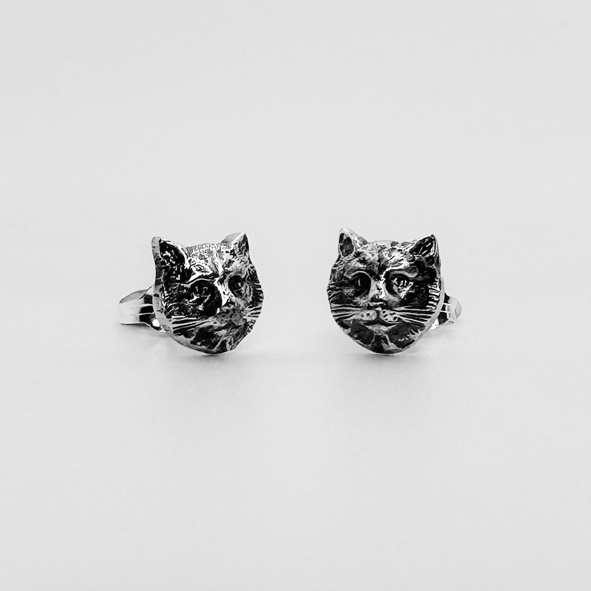 A pair of solid silver cat stud earrings with a butterfly back. handmade in nottingham by bottlebee