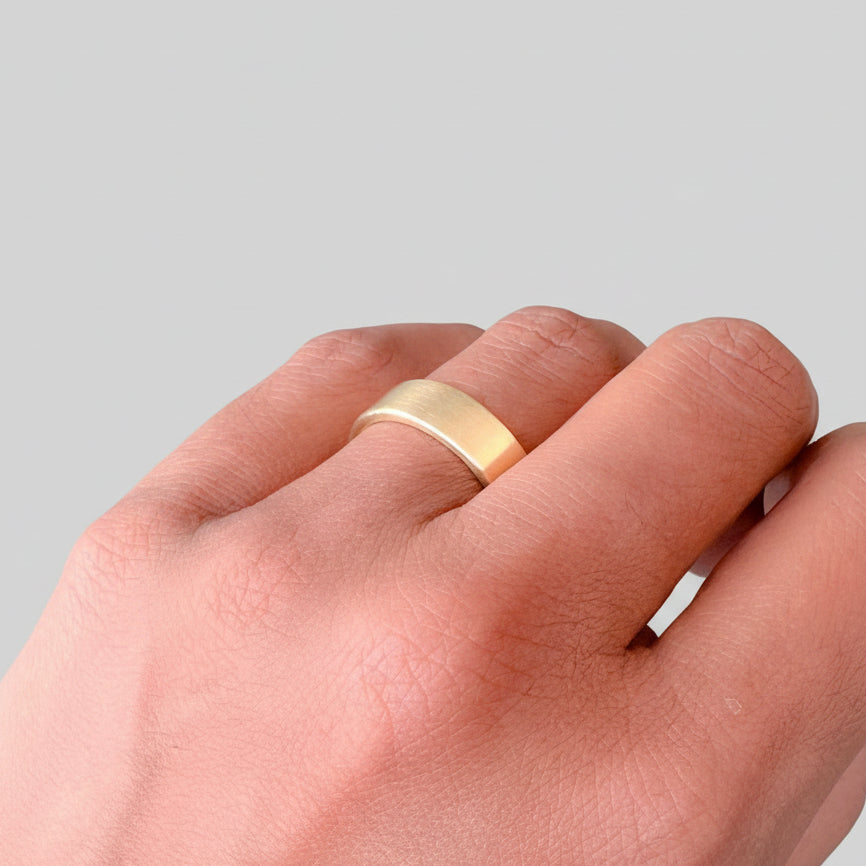 Solid gold sustainable bespoke wedding ring on a woman's finger against a plain background made in nottingham