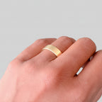 Solid gold sustainable bespoke wedding ring on a woman's finger against a plain background made in nottingham