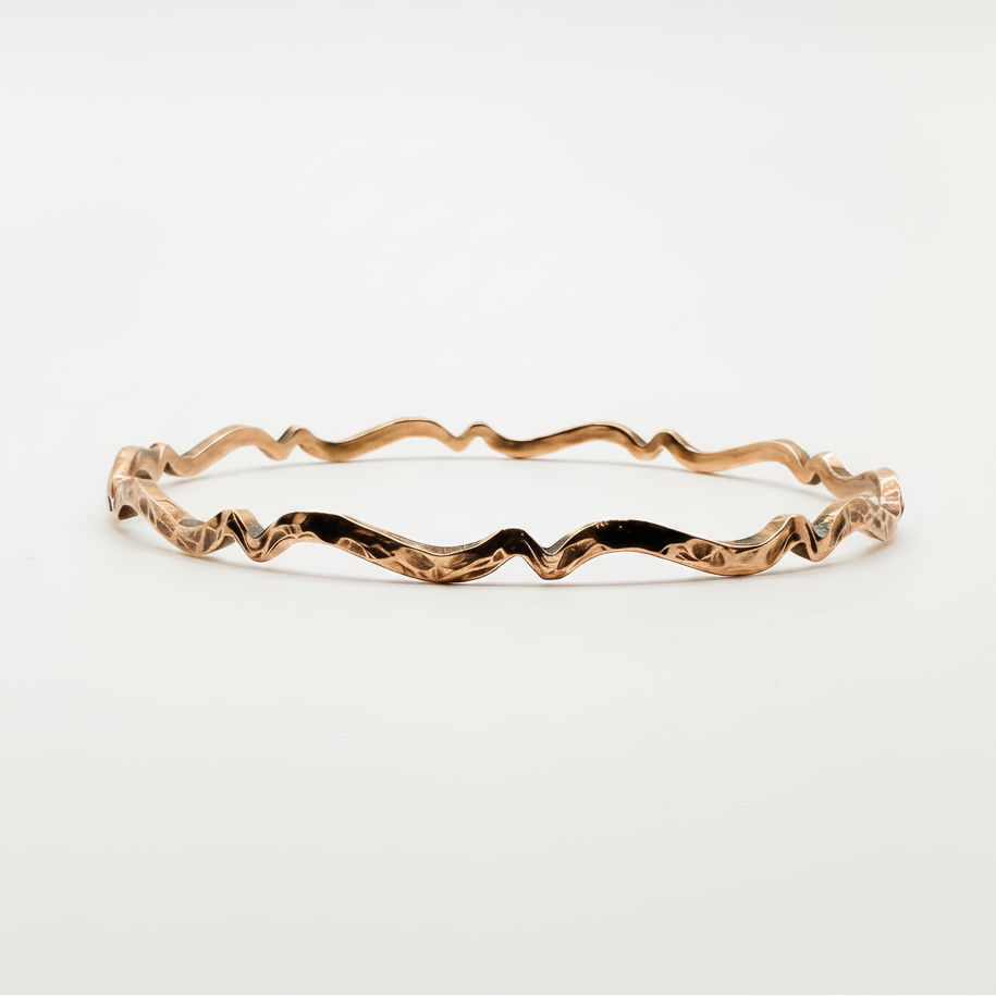 copper wavy handmade bracelet on a light grey background