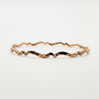 copper wavy handmade bracelet on a light grey background