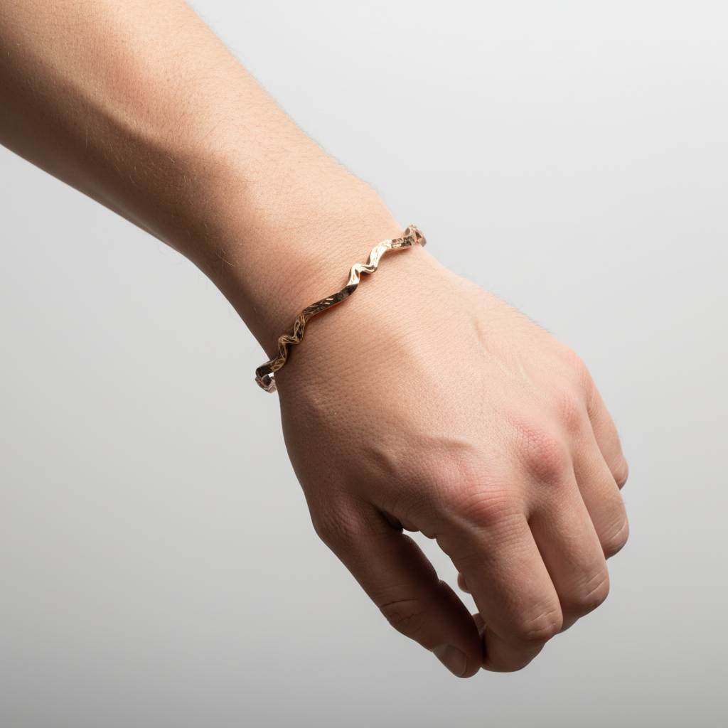 Mans hand wearing a copper bracelet on a light grey background, handmade jewellery