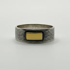 Sterling silver patterned and oxidised ring with a gold accent on a white background
