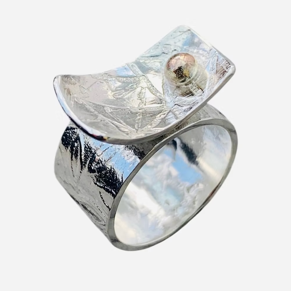 Silver ring with a textured surface and an 18ct gold ball on a white background handmade in nottingham by a sustainable jeweller
