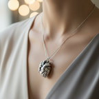 Silver necklace with a heart pendant worn by a woman in a grey v-neck top in a softly lit indoor setting