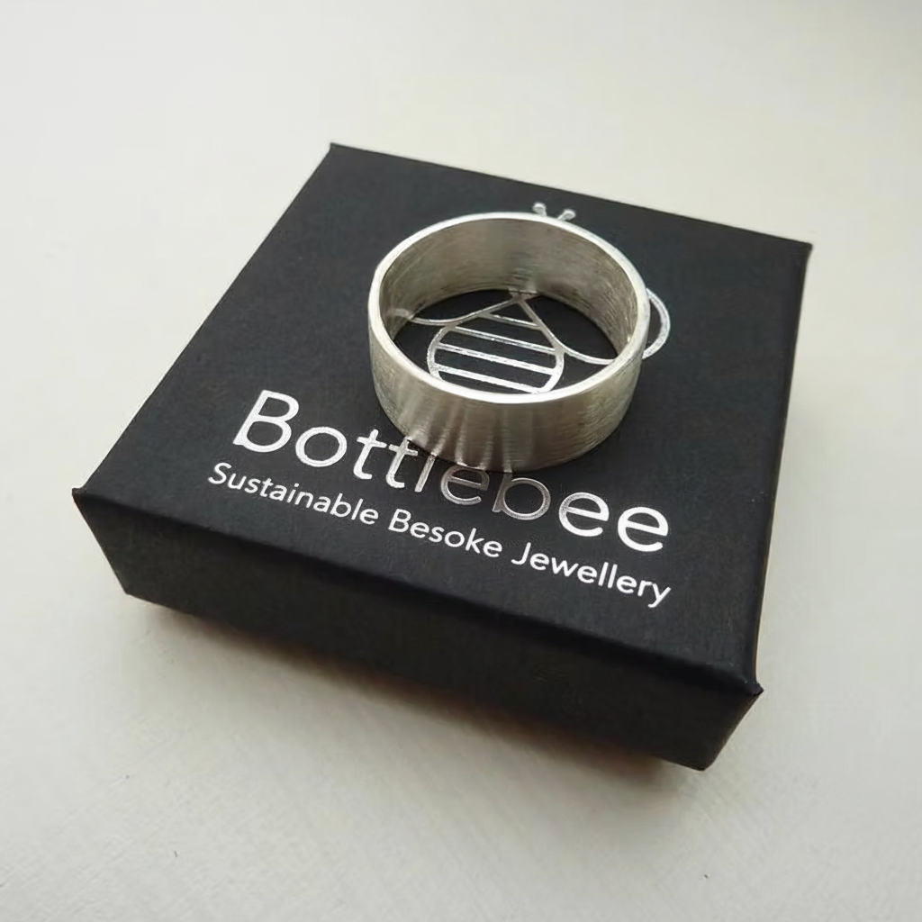 handmade silver mans wedding ring on a 'bottlebee' branded box on a white background