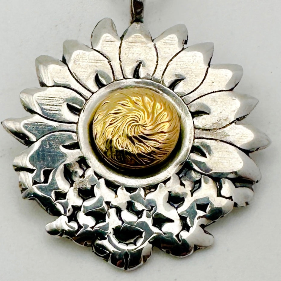 close up of butterflower Sterling silver and 18ct gold necklace with a sterling silver sunflower and butterfly shaped pendant on a white background. The butterflies are merging with the sunflower and the head of the sunflower in the middle of the pendant is made from 18ct gold. Handmade jewellery in Nottingham