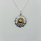 silver and gold necklace with a sunflower and butterfly shaped pendant on a white background. The butterflies are merging with the sunflower and the head of the sunflower in the middle of the pendant is made from 18ct gold. Handmade jewellery in Nottingham