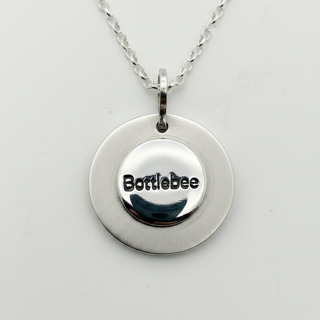 back of sunflower Silver necklace with 'bottlebee' stamped on it to show who made it on a light gray background