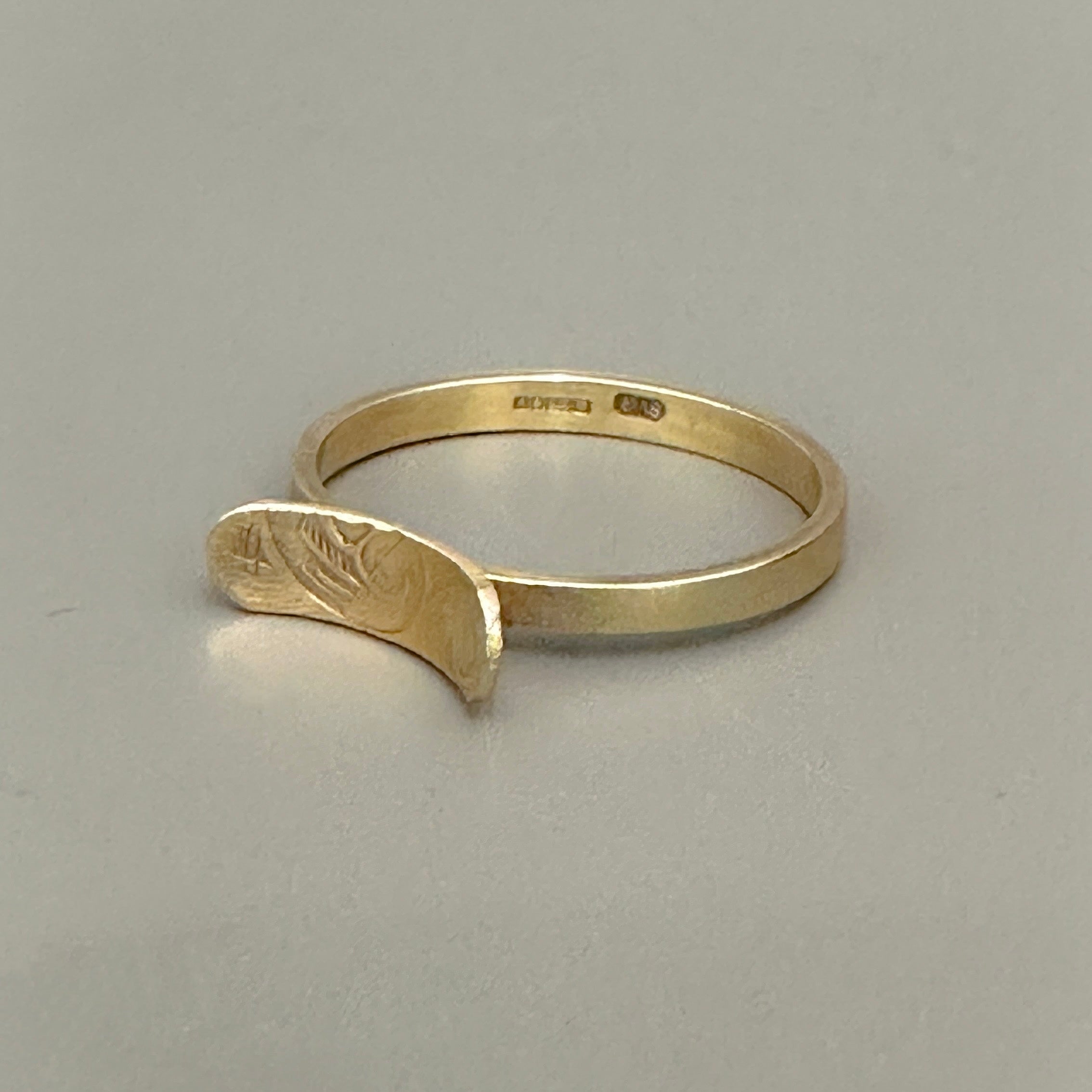 Gold engagement ring with a unique design on a gryy background