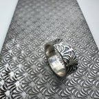 unique art deco jewellery silver wedding ring band for a man or woman or unisex resting on a pattern plate on a light grey background handmade sustainable bespoke jewellery Nottingham