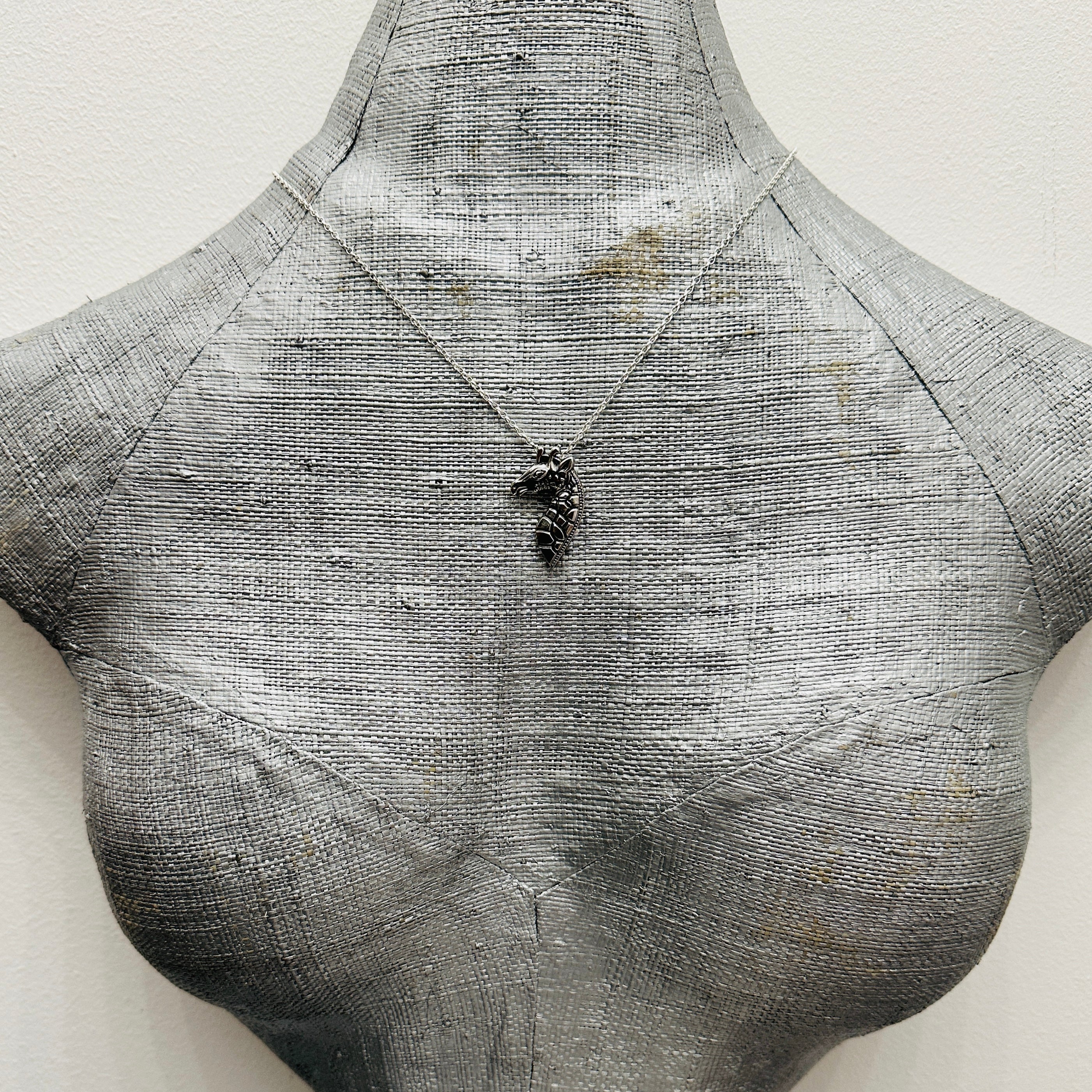 Silver necklace made in Nottingham with recycled silver showing a giraffe pendant on a grey bust